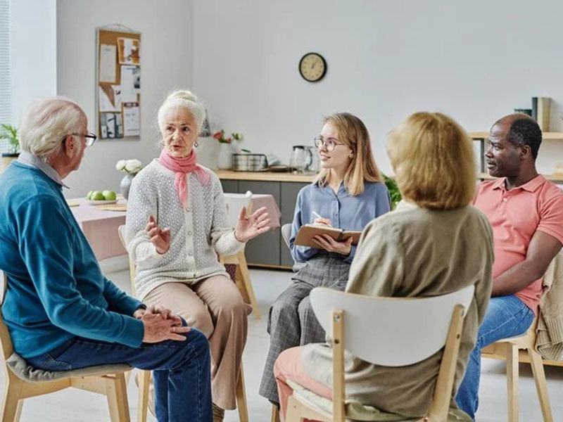 A group of individuals sitting in a circle, engaged in discussion