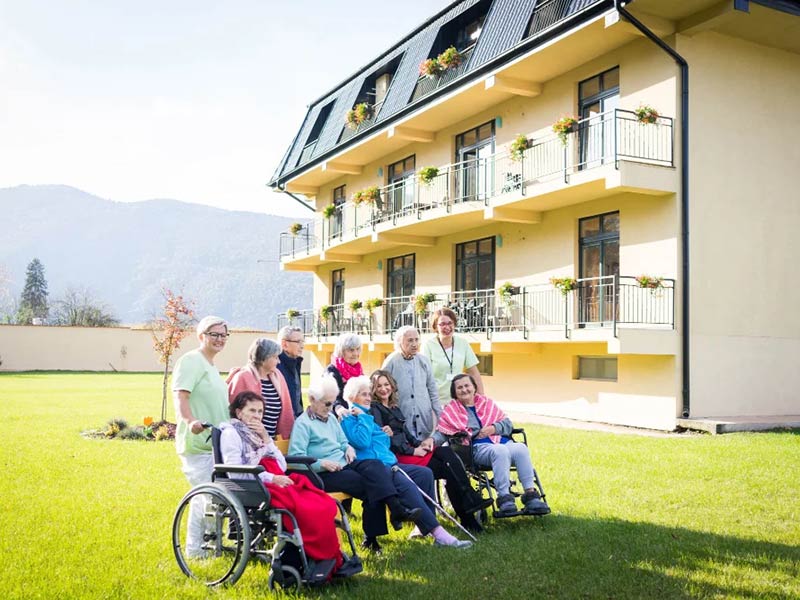 A group of elderly individuals in wheelchairs gathered outside a building