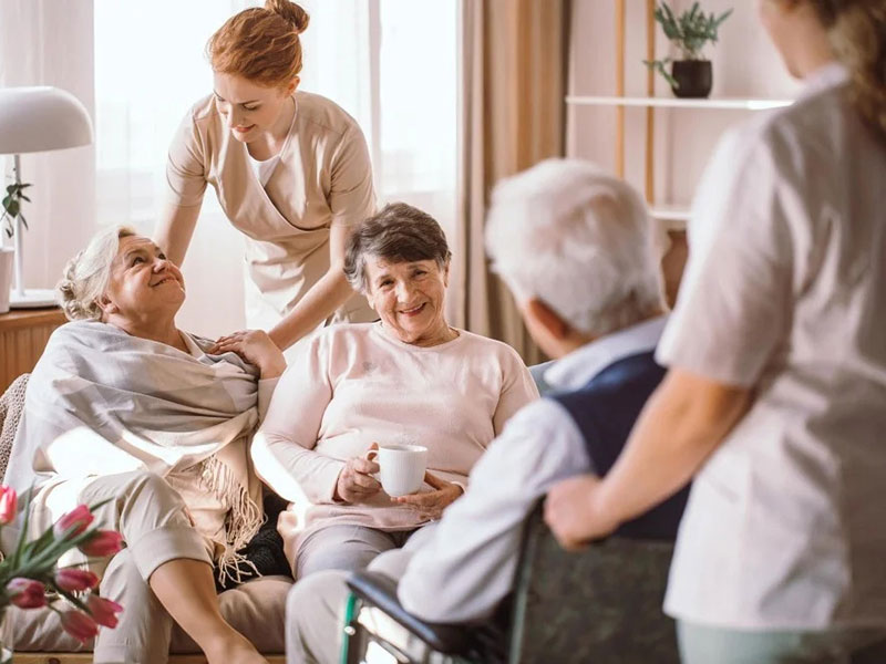 Several senior citizens seated in a warm living room, sharing stories