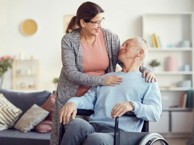 A woman in a wheelchair provides help to an elderly man