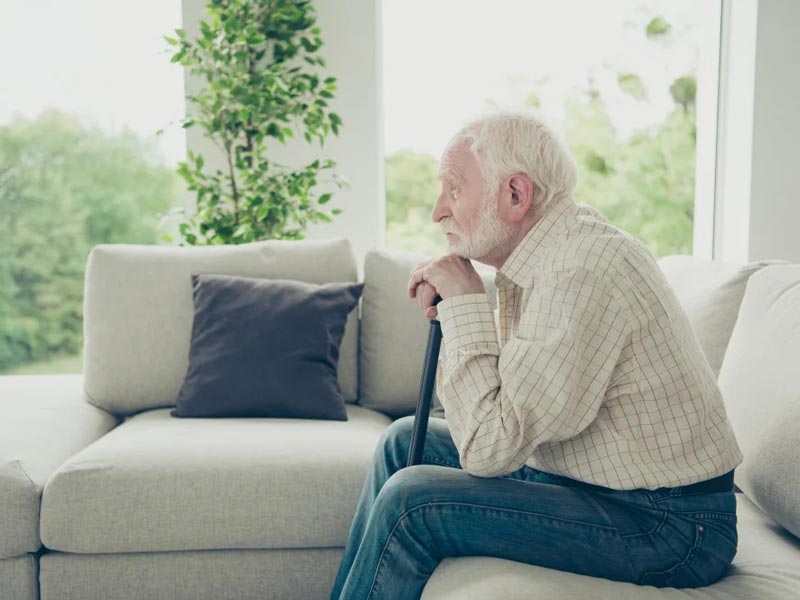 senior man with cane sitting on couch